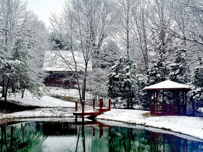 a park with a gazebo and a pond in the snow at Breath of Heaven Cabin- Hot Tub, Deck, Pond, PETS in Logan