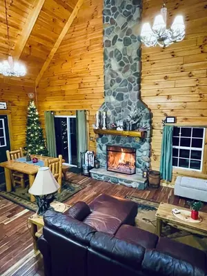 a living room with a fireplace in a log cabin at Breath of Heaven Cabin- Hot Tub, Deck, Pond, PETS in Logan