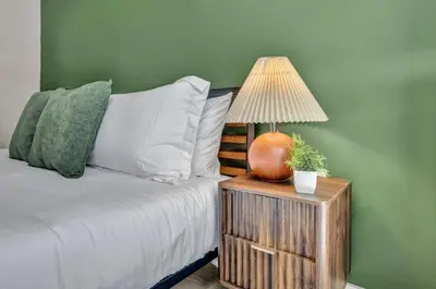 a bed with a table with a lamp on it at Little Italy & CWRU w King BedGymParkingWD in Cleveland