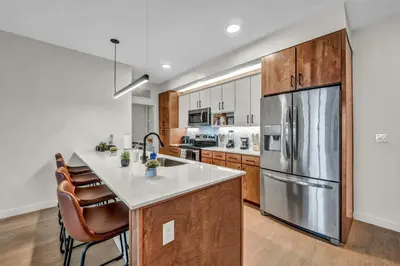 a kitchen with wooden cabinets and a stainless steel refrigerator at Walk to CWRU w KingBed Balcony Gym Parking WD in Cleveland
