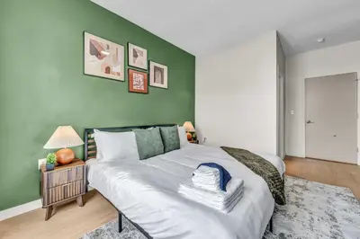 a bedroom with a large bed with a green wall at Walk to CWRU w KingBed Balcony Gym Parking WD in Cleveland