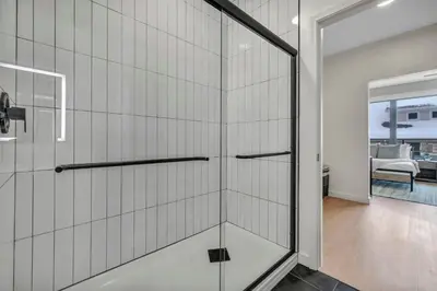 a glass shower door in a bathroom with a living room at Walk to CWRU w KingBed Balcony Gym Parking WD in Cleveland