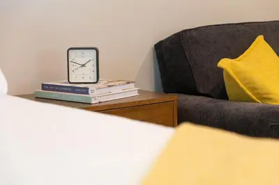 a clock sitting on a stack of books next to a couch at Perfectly Petite! in Ashland