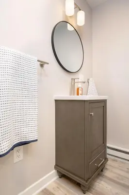 a bathroom with a brown cabinet and a mirror at Perfectly Petite! in Ashland