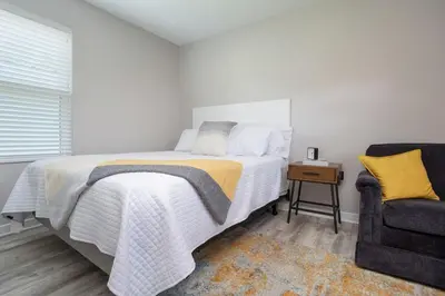 a white bedroom with a bed and a chair at Perfectly Petite! in Ashland
