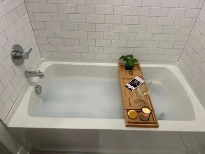 a white bath tub with a wooden tray in it at Modern apt in Cincy stadiums and with river views in Cincinnati