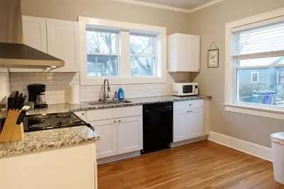 a kitchen with white cabinets and a black stove top oven at The Avon - Quaint Home in Downtown Lexington in Lexington
