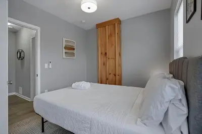 a bedroom with a white bed and a wooden door at Modern 2BR Yale Townhouse Near Downtown Columbus in Columbus