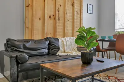 a living room with a black leather couch and a table at Modern 2BR Yale Townhouse Near Downtown Columbus in Columbus
