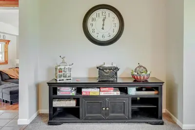 a black entertainment center with a clock on the wall at Hocking Hills Hideaway with Hot Tub and Games in Rockbridge