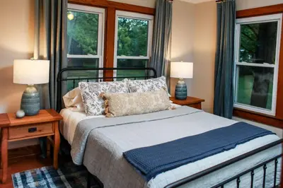 a bedroom with a bed with two lamps and two windows at Alice Rocks - Pet Friendly, Firepit, WiFi in Frenchburg