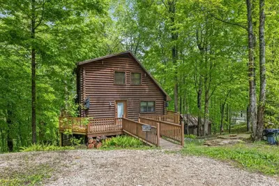 a log cabin in the woods with a large deck at Birdsong- Hot Tub, Game Room, Firepit, WiFi in Stanton
