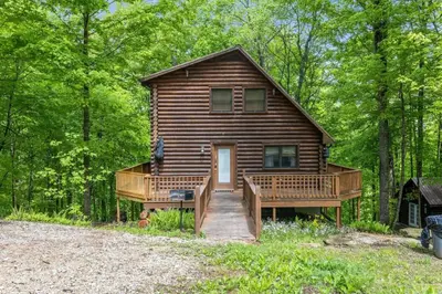a log cabin in the woods with a porch and a deck at Birdsong- Hot Tub, Game Room, Firepit, WiFi in Stanton