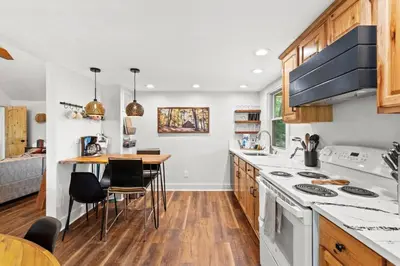 a kitchen with wooden cabinets and a table with chairs at Furnace Mountain Retreat- Hot Tub, Fireplace, WiFi in Stanton