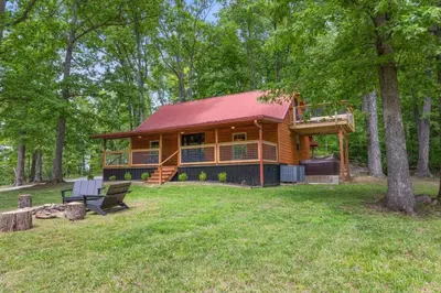 a log cabin in the woods with a deck at Furnace Mountain Retreat- Hot Tub, Fireplace, WiFi in Stanton
