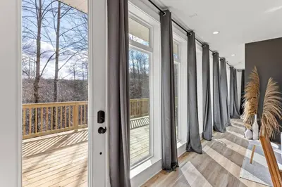 a balcony with glass doors and a wooden deck at Primrose- Hot Tub, Firepit, Wraparound Deck, WiFi in Wellington