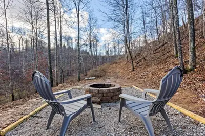 two chairs sitting next to a fire pit in the woods at Primrose- Hot Tub, Firepit, Wraparound Deck, WiFi in Wellington