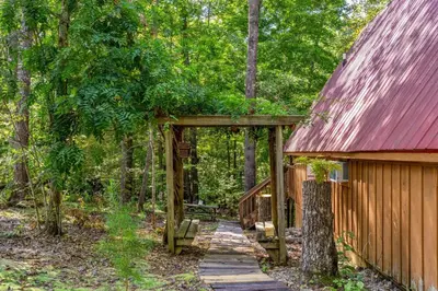 a wooden pathway leading to a cabin in the woods at Sugar Shack - Cave Run Lake OR Red River Gorge KY in Wellington