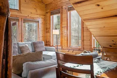 a log cabin living room with a couch and windows at Beary Cozy- No Pet Fee, Hot Tub, Fireplace, WiFi in Slade