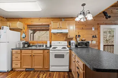 a kitchen with wooden cabinets and a white stove top oven at Beary Cozy- No Pet Fee, Hot Tub, Fireplace, WiFi in Slade