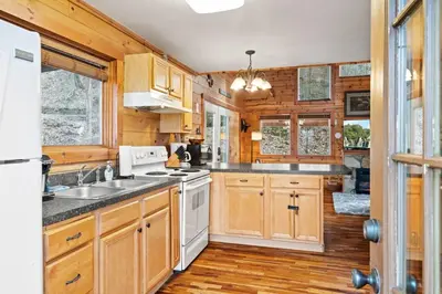 a kitchen with wooden cabinets and white appliances at Beary Cozy- No Pet Fee, Hot Tub, Fireplace, WiFi in Slade