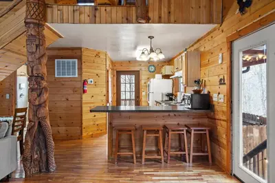 a kitchen with wooden walls and a counter with stools at Beary Cozy- No Pet Fee, Hot Tub, Fireplace, WiFi in Slade