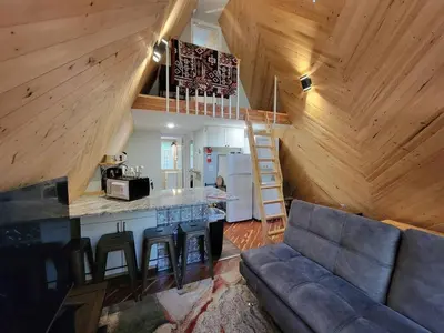 a living room with a couch and a kitchen in a cabin at A Frame of Mind - near Red River Gorge KY in Jeffersonville