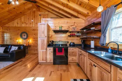 a kitchen with a stove top oven in a cabin at Cozy Canopy- Hot Tub, Firepit, Covered Deck, WiFi in Stanton