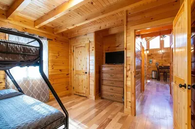 a bedroom in a log cabin with a bed and a tv at Cozy Canopy- Hot Tub, Firepit, Covered Deck, WiFi in Stanton