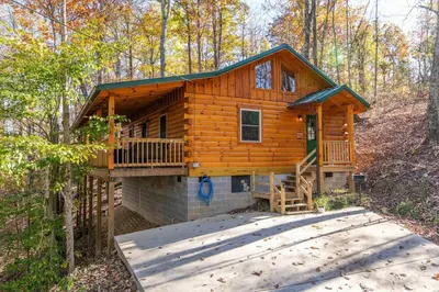 a log cabin in the woods with a deck at Cozy Canopy- Hot Tub, Firepit, Covered Deck, WiFi in Stanton