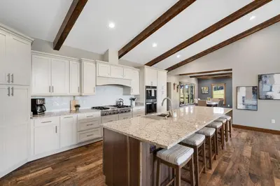 a kitchen with white cabinets and a large island with bar stools at Calaboose Retreat- Hot Tub , Pool Table, Fireplace in Campton