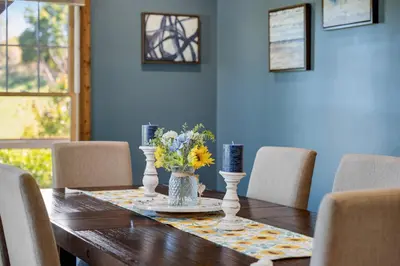 a dining room table with a vase of flowers on it at Calaboose Retreat- Hot Tub , Pool Table, Fireplace in Campton