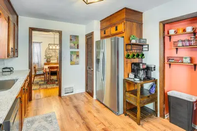 a kitchen with a stainless steel refrigerator and wooden cabinets at Bring the Family! Mid-Century Modern Gem in Euclid in Euclid