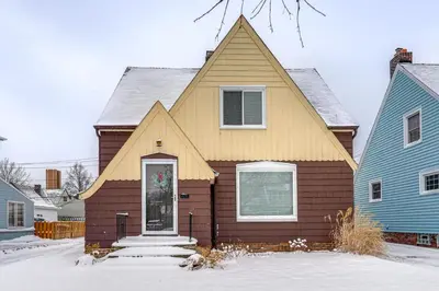 a brown house with a pointed roof in the snow at Bring the Family! Mid-Century Modern Gem in Euclid in Euclid
