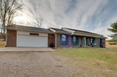 a small brick house with a white garage at 5-Acre Hocking Hills Hideaway! Pet-Friendly Home in New Plymouth