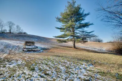 a bench in a field with a tree on a hill at 5-Acre Hocking Hills Hideaway! Pet-Friendly Home in New Plymouth
