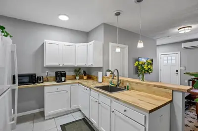 a kitchen with white cabinets and a wooden counter top at Modern Columbus 2BR Near COSI & Arena District in Columbus