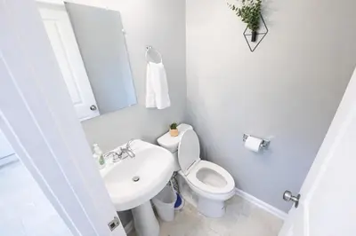 a white bathroom with a toilet and a sink at Modern Columbus 2BR Near COSI & Arena District in Columbus