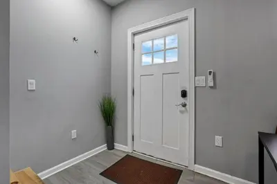 a white hallway with a door and a potted plant at Modern Columbus 2BR Near COSI & Arena District in Columbus
