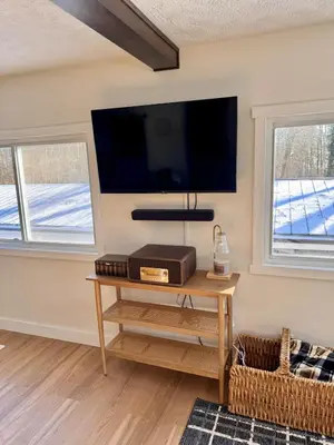 a living room with a table and a tv on the wall at Logan’s Lookout over Mohican - Modern Farmhouse in Loudonville