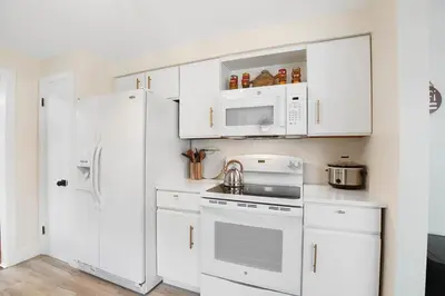 a kitchen with white cabinets and a white refrigerator at The Sleepy Tiki - game room, tiki lounge, firepit in Mason