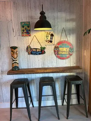 a wooden bar with two stools and signs on a wall at The Sleepy Tiki - game room, tiki lounge, firepit in Mason