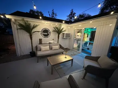 a patio with a couch and a coffee table in front of a building at The Sleepy Tiki - game room, tiki lounge, firepit in Mason