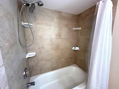 a bathroom with a shower and a white tub at Mason Ohio Home large private yard firepit game room in Mason
