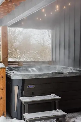 a hot tub in a room with a window at Modern Cabin next to Salt Fork State Park
