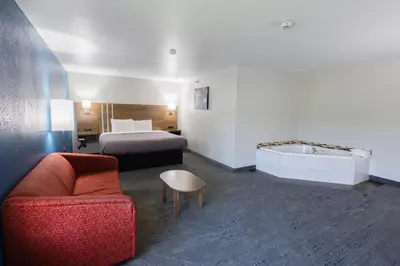 a hotel room with a bed and a couch and a tub at Countryside Inn and Suites in Mount Orab