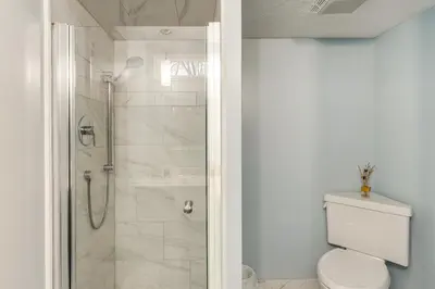 a white bathroom with a shower and a toilet at Close to Hospitals and Downtown Cleveland Home in North Olmsted