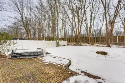 a yard covered in snow with a fence and trees at Close to Hospitals and Downtown Cleveland Home in North Olmsted