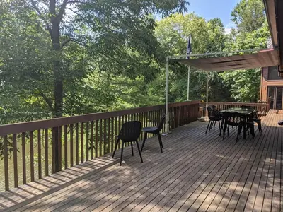a deck with chairs and a table and umbrella at Nature Spa House | •Pool •Hot Tub •Sauna •Pvt Lake in New Richmond