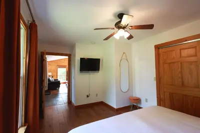 a bedroom with a ceiling fan and a living room at Golden goat cabin in Logan